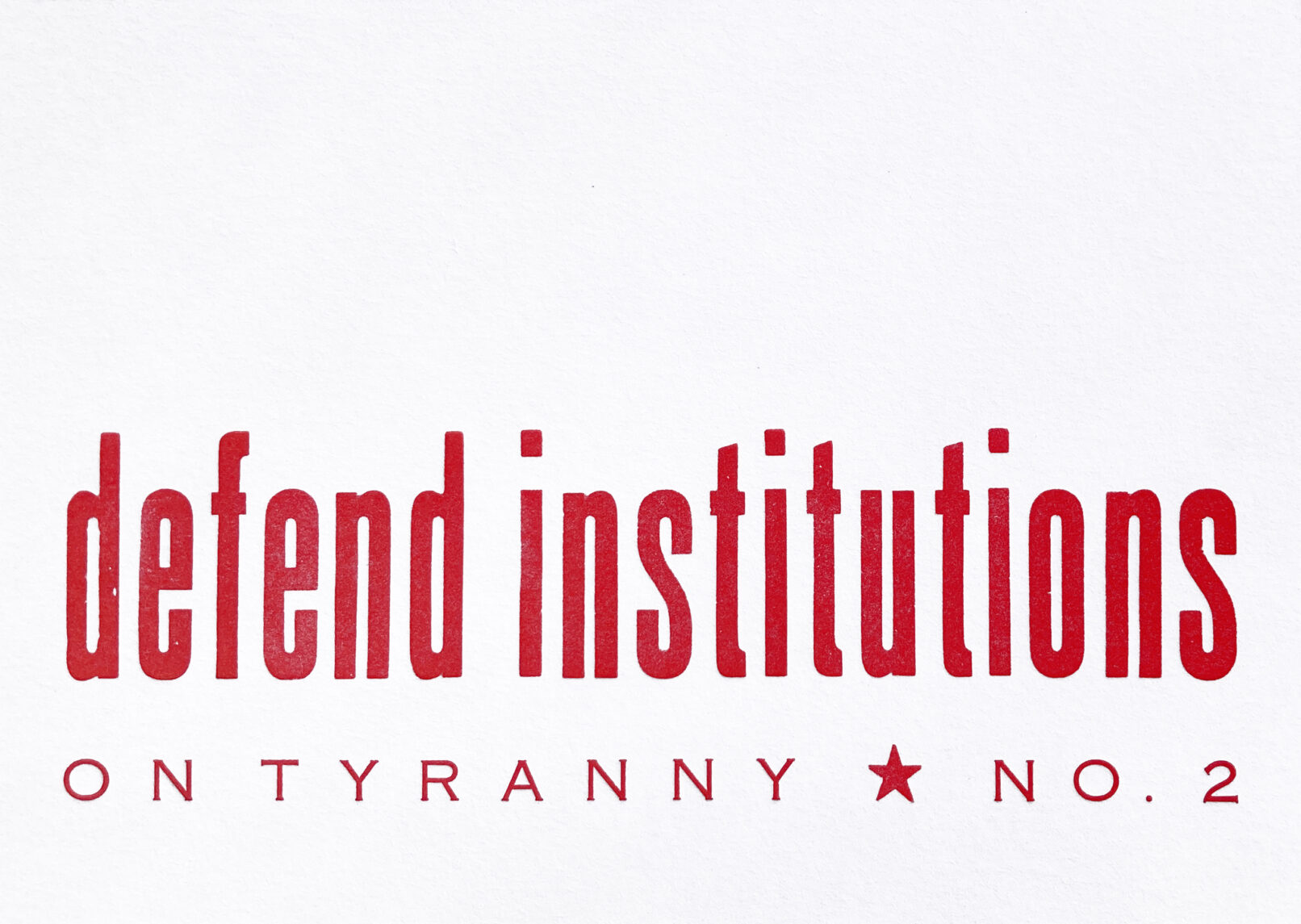 Letterpress print in red ink on white paper with text that reads "Defend Institutions On Tyranny No. 2"