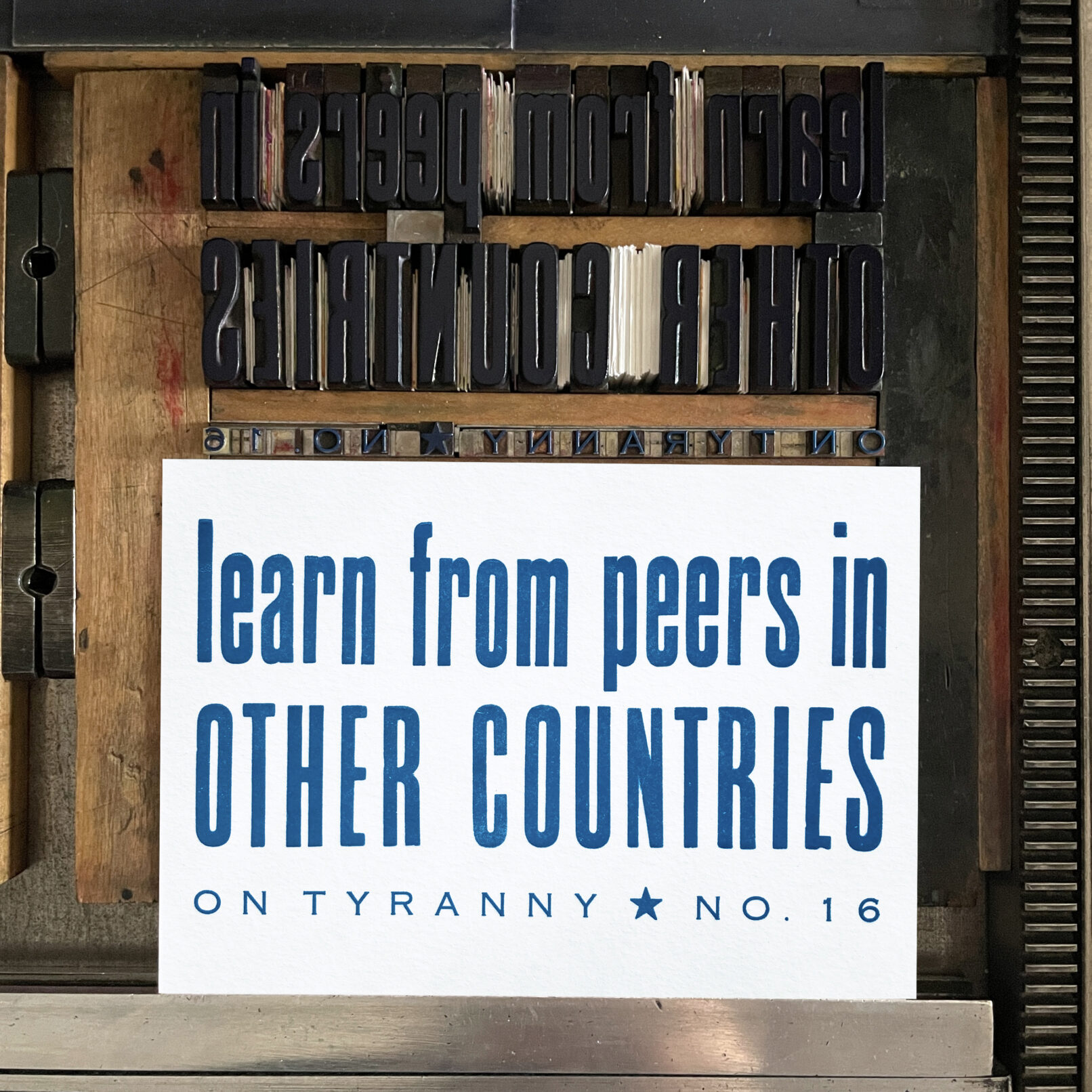 Letterpress print on Vandercook press bed. Printed in blue ink on white paper, the text reads "Learn from Peers in Other Countries On Tyranny No. 16"