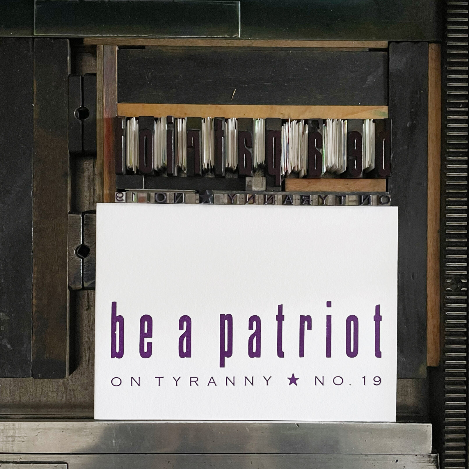 Letterpress print on Vandercook press bed. Printed in purple ink on white paper with text that reads "Be a Patriot On Tyranny No. 19"