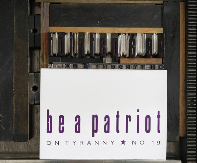 Letterpress print on Vandercook press bed. Printed in purple ink on white paper with text that reads "Be a Patriot On Tyranny No. 19"