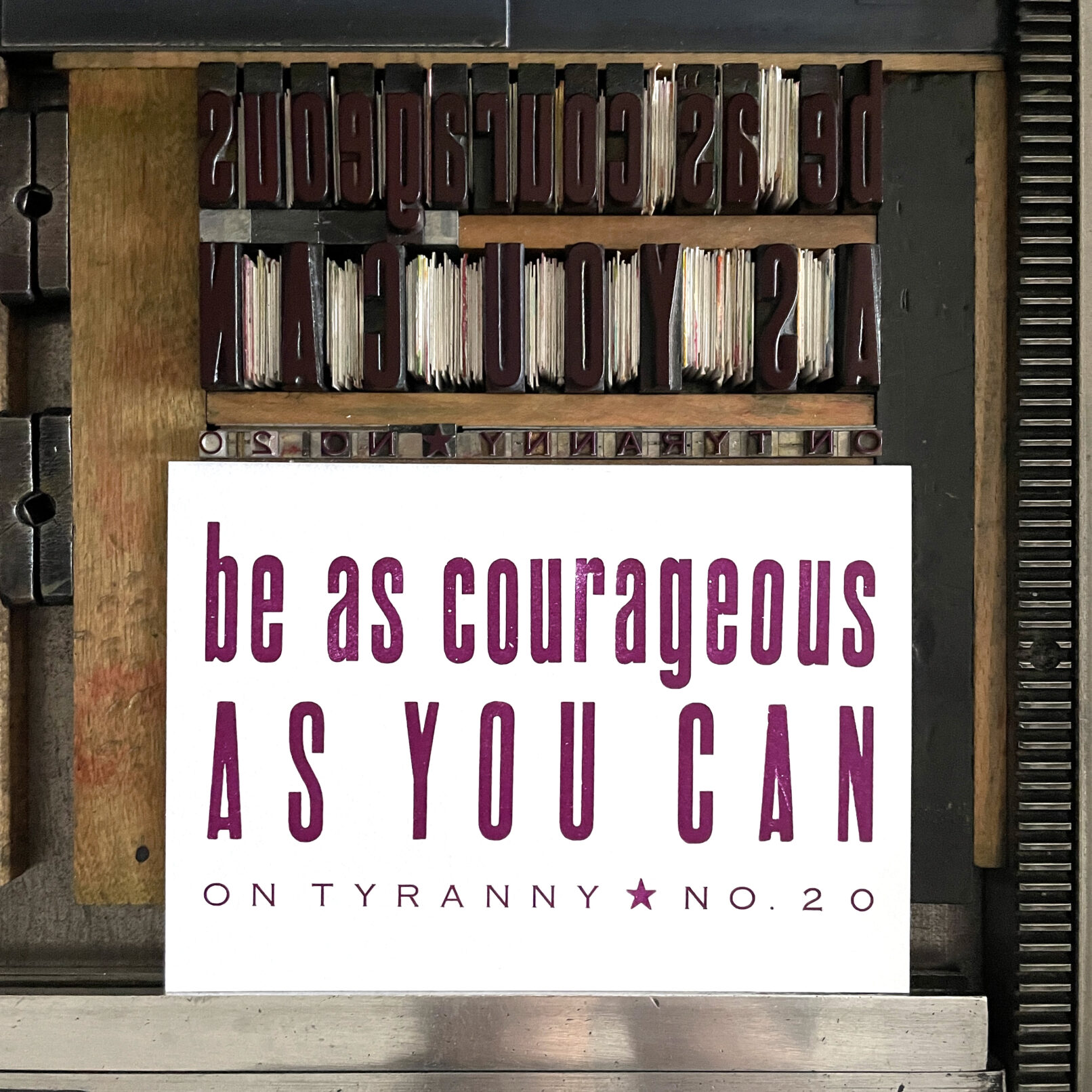 Letterpress print on Vandercook press bed. Printed in plum purple ink on white paper, the text reads "Be As Courageous As You Can On Tyranny No. 20."