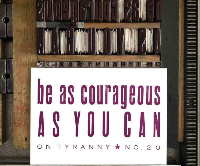 Letterpress print on Vandercook press bed. Printed in plum purple ink on white paper, the text reads "Be As Courageous As You Can On Tyranny No. 20."