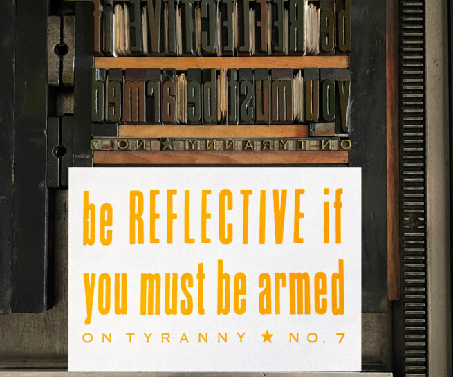Letterpress print on Vandercook press bed. Printed in yellow ink on white paper, the text reads "Be Reflective if You Must Be Armed On Tyranny No. 7."