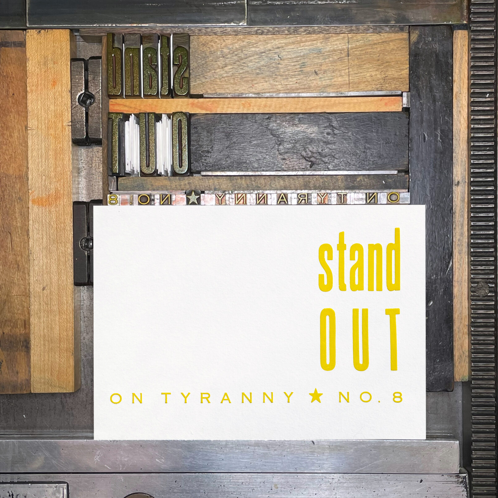 Letterpress print on Vandercook press bed. Printed in yellow ink on white paper, the text reads "Stand Out On Tyranny No. 8"