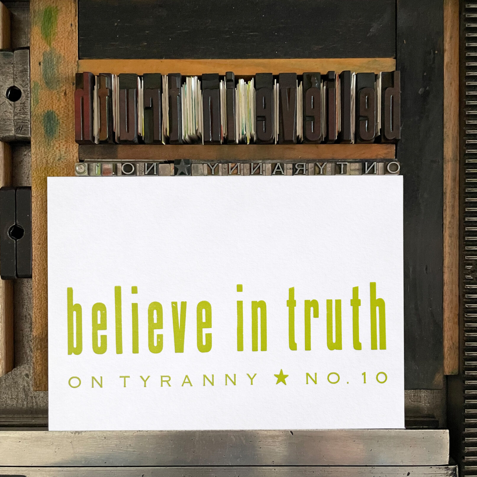 Letterpress print on Vandercook press bed. Printed in yellow-green ink on white paper, the text reads "Believe in Truth On Tyranny No. 10."