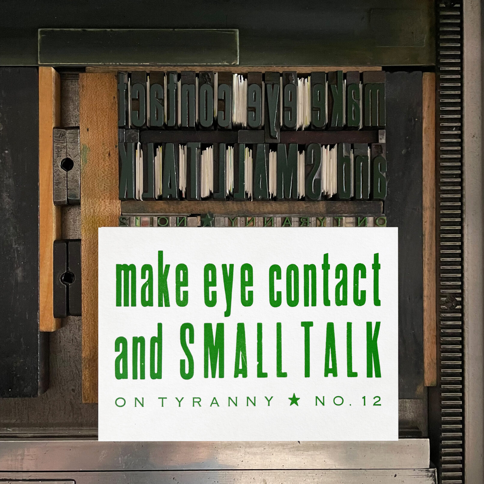 Letterpress print on Vandercook press bed. Printed in green ink on white paper, the text reads "Make Eye Contact and Small Talk On Tyranny No. 12."