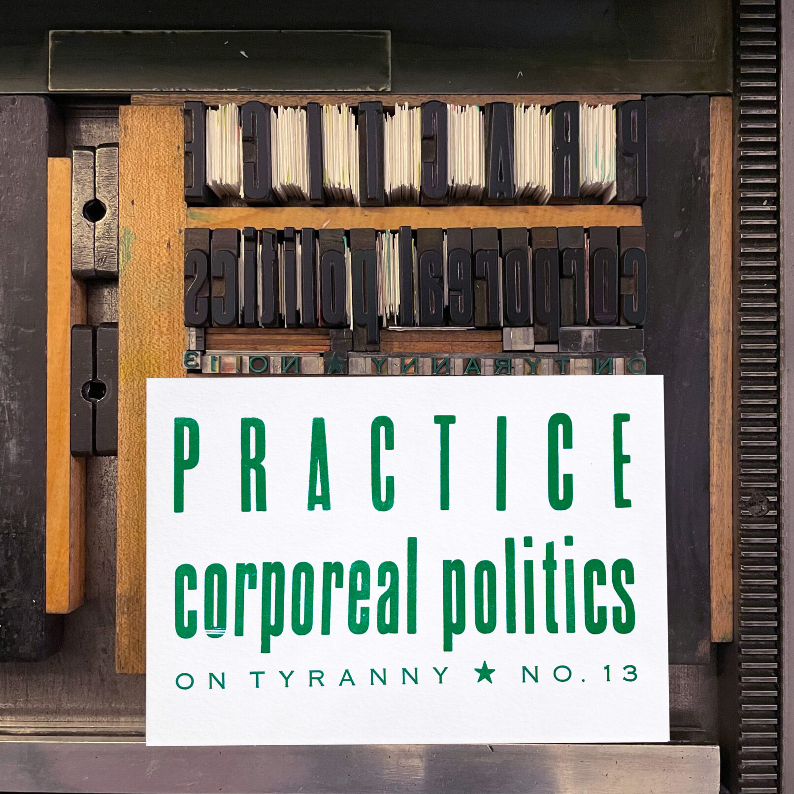 Letterpress print on Vandercook press bed. Printed in teal green ink on white paper, the text reads "Practice Corporeal Politics On Tyranny No. 13"